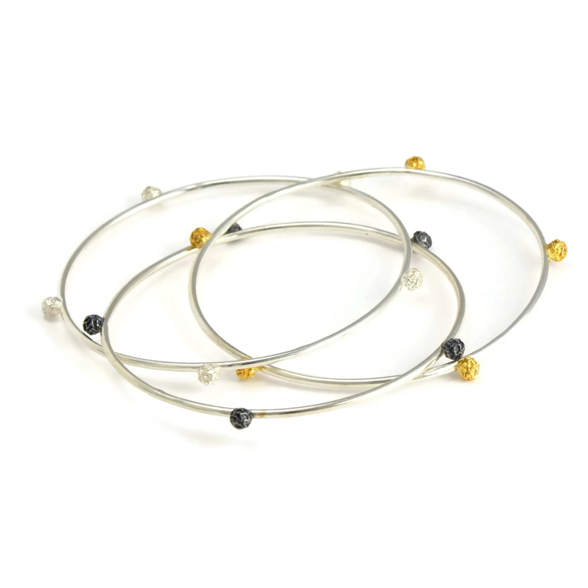 A Set of three bangles, with stellar peppercorns design accented with gold vermiel, dark and bright silver sterling