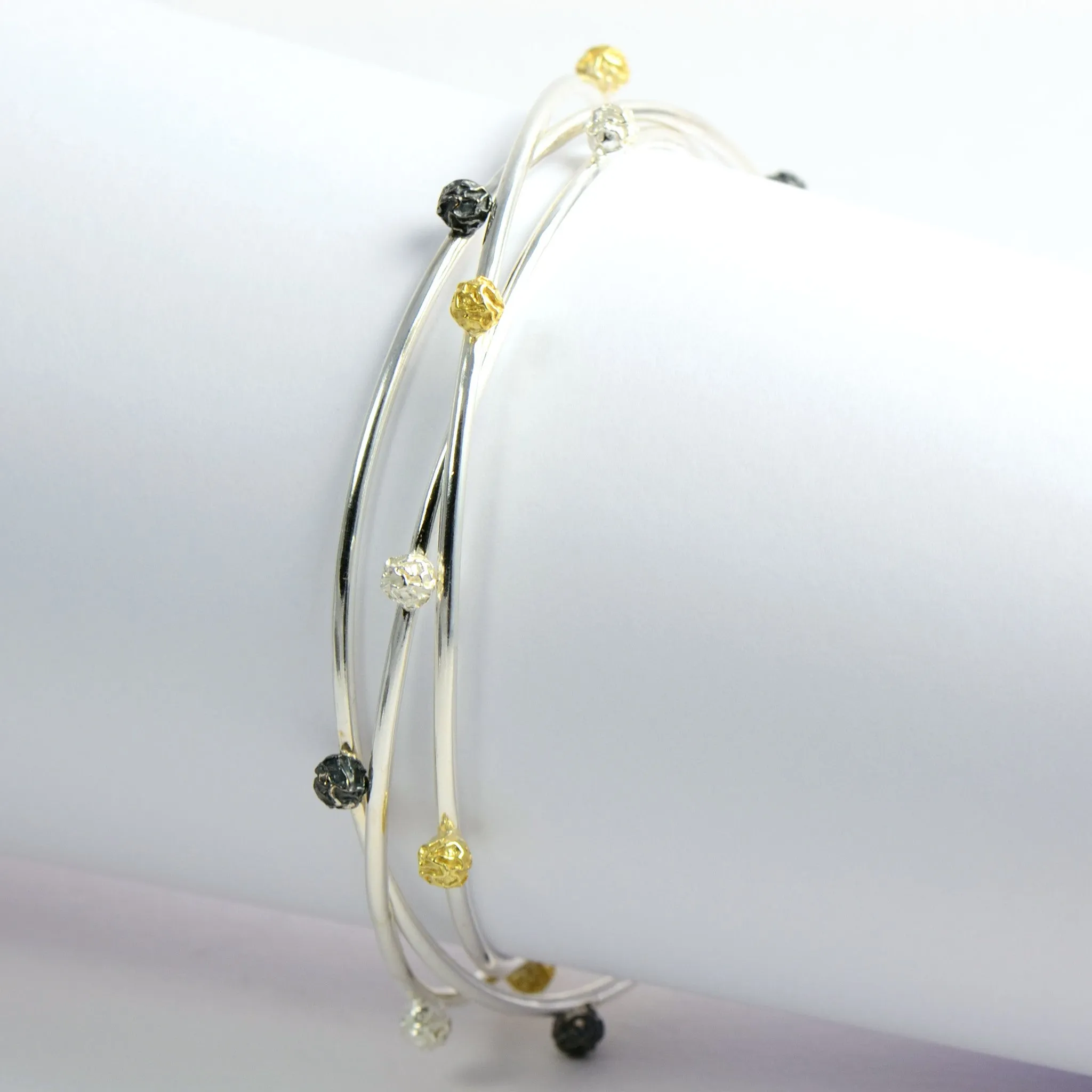A Set of three bangles, with stellar peppercorns design accented with gold vermiel, dark and bright silver sterling
